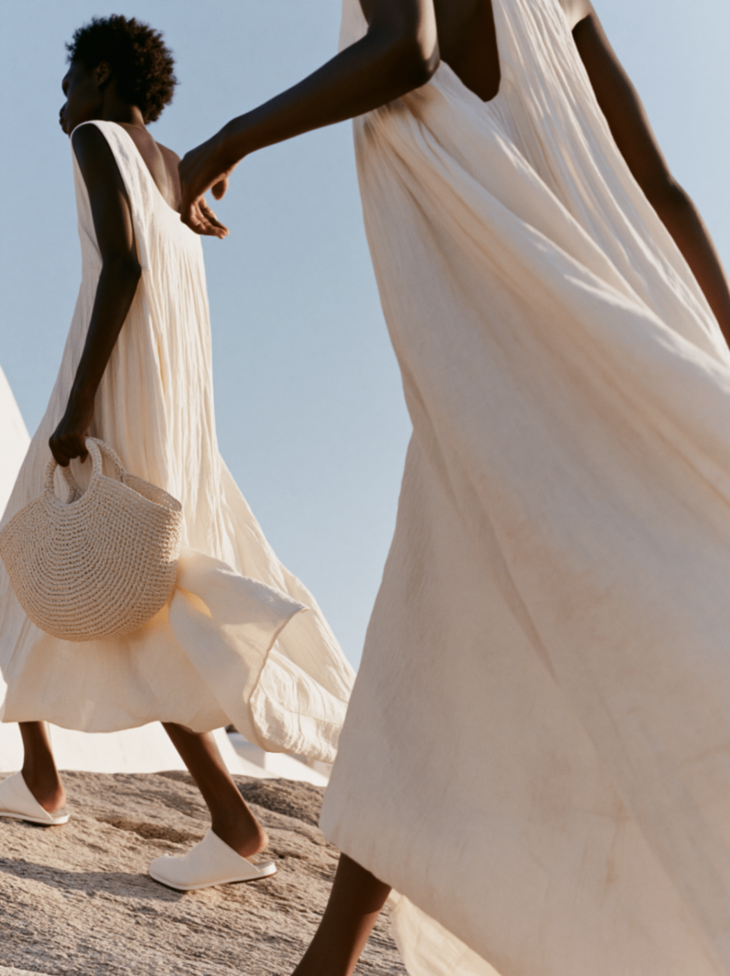Two models walking in flowing cream dresses